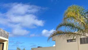 Un edificio de varios pisos con balcones, rodeado de vegetación y palmeras.