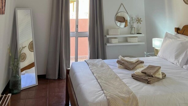 Una habitación de hotel con una cama, una mesita de noche, un espejo y una lámpara colgante.