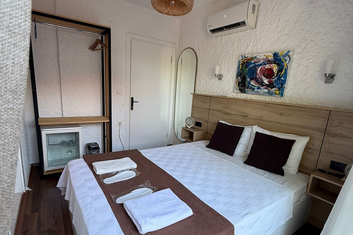 Een hotelkamer met een groot bed, een nachtkastje, een spiegel, een wandairco en een schilderij.