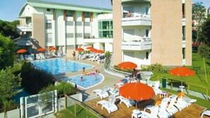 Ein Hotel mit Schwimmbad, Liegestühlen und Sonnenschirmen.