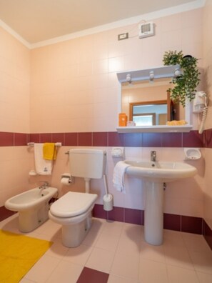 Un baño con bidé, inodoro, lavabo y un espejo sobre el lavabo.