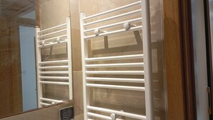 A bathroom with a white towel rack, a mirror, and a tiled wall. - VIP Tunisia  (Halq al Wadi)