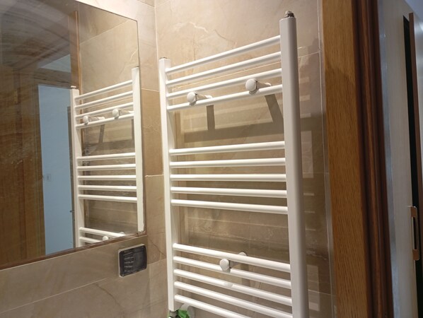 A bathroom with a white towel rack, a mirror, and a tiled wall. - VIP Tunisia (Halq al Wadi)