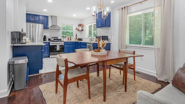 Una cocina moderna con armarios azules, una mesa de comedor de madera y un amplio ventanal con persianas.