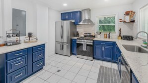 Una cocina moderna con armarios azules, electrodomésticos de acero inoxidable y una encimera de mármol blanco.