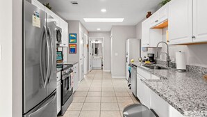 A modern kitchen with stainless steel appliances, a granite countertop, and white cabinetry.