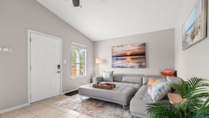 A modern living room with a grey sectional sofa, a large abstract painting, and a potted plant.
