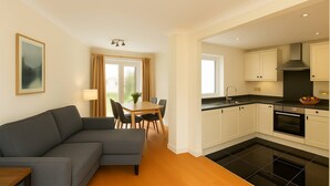 A modern kitchen with black tiles, white cabinets, and a dining area with a grey sofa and a table. - 4-bed Home in Maidenhead (Maidenhead)