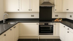 A modern kitchen with white cabinets, a black countertop, and a built-in oven. - 4-bed Home in Maidenhead (Maidenhead)