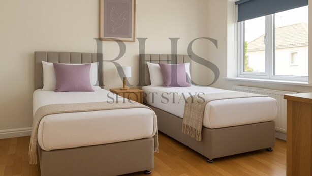 A bedroom with two beds, a nightstand, a window with a view, and a framed picture on the wall. - 4-bed Home in Maidenhead (Maidenhead)