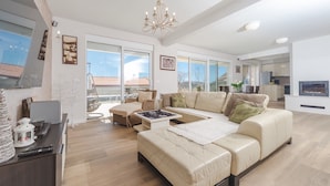 Un salón amplio con un sofá beige, una mesa de centro y un sillón colgante. Una ventana grande ofrece vistas al exterior.