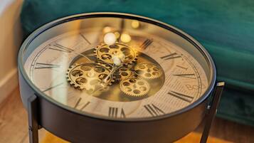 A clock with Roman numerals and visible gears, placed on a stand.