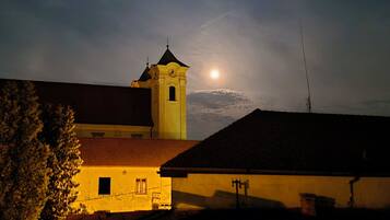 A building with a clock tower, a red roof, and a visible moon in the sky.