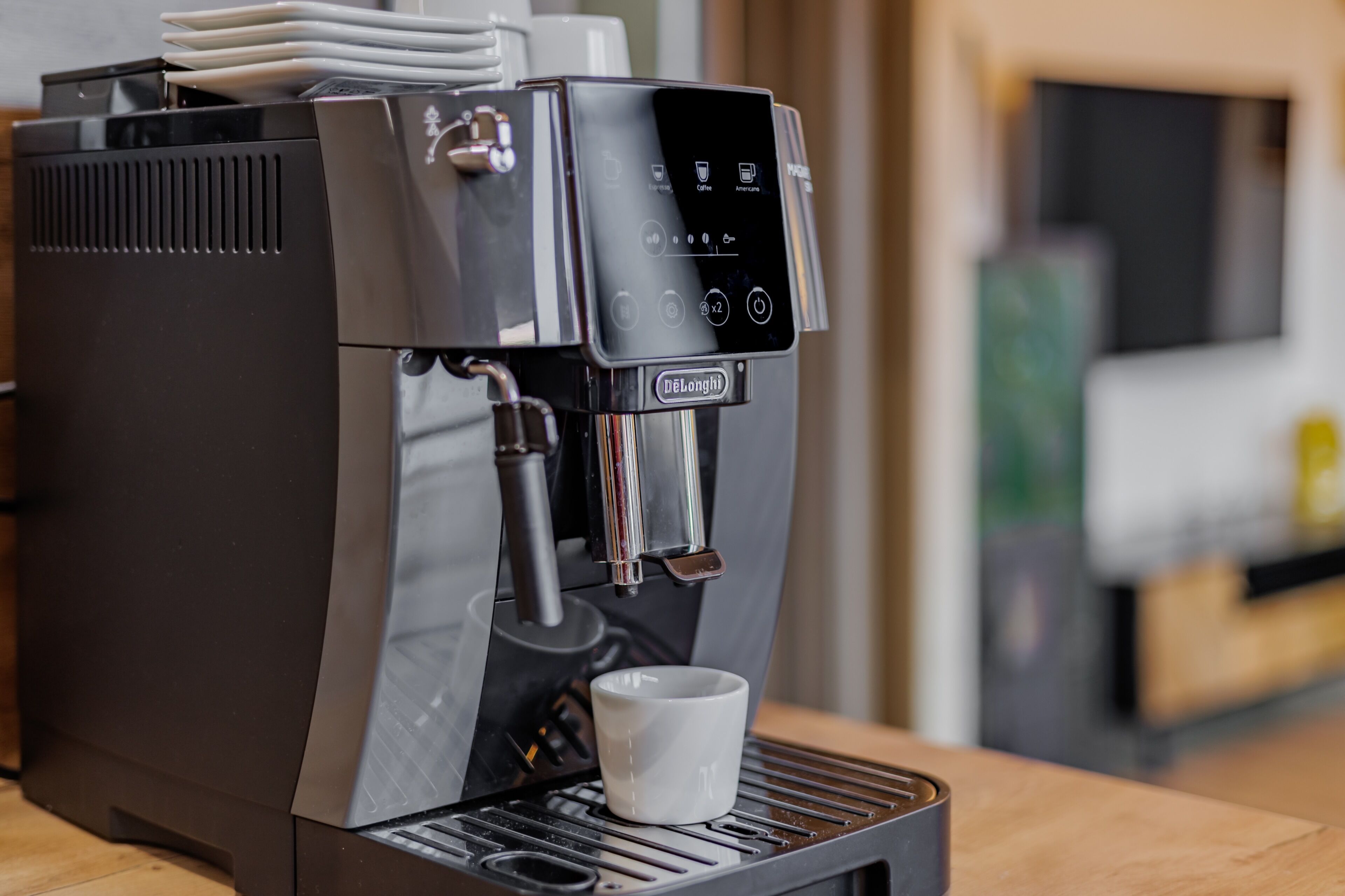 A DeLonghi espresso machine with a digital interface, a cup holder, and a tray below.