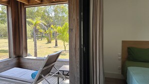 Une chambre avec un lit, une chaise et une vue sur un jardin.
