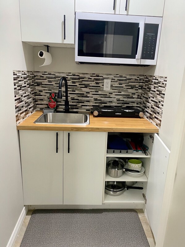 Una cocina compacta con microondas, lavabo y armarios de almacenamiento.