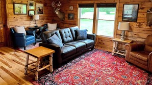L’intérieur d’un chalet accueillant, avec un canapé en cuir, une table basse en bois et un tapis à motifs.
