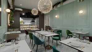 Restaurante con mesas dispuestas para comer, una cocina al fondo e iluminación decorativa.