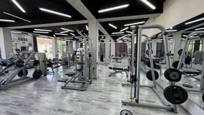 Un gimnasio con equipamiento de halterofilia variado, espejos y un piso de madera pulida.