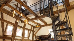 A spacious loft with exposed wooden beams, a spiral staircase, and hanging light fixtures. - Maison Da Silva (Oberderdingen)