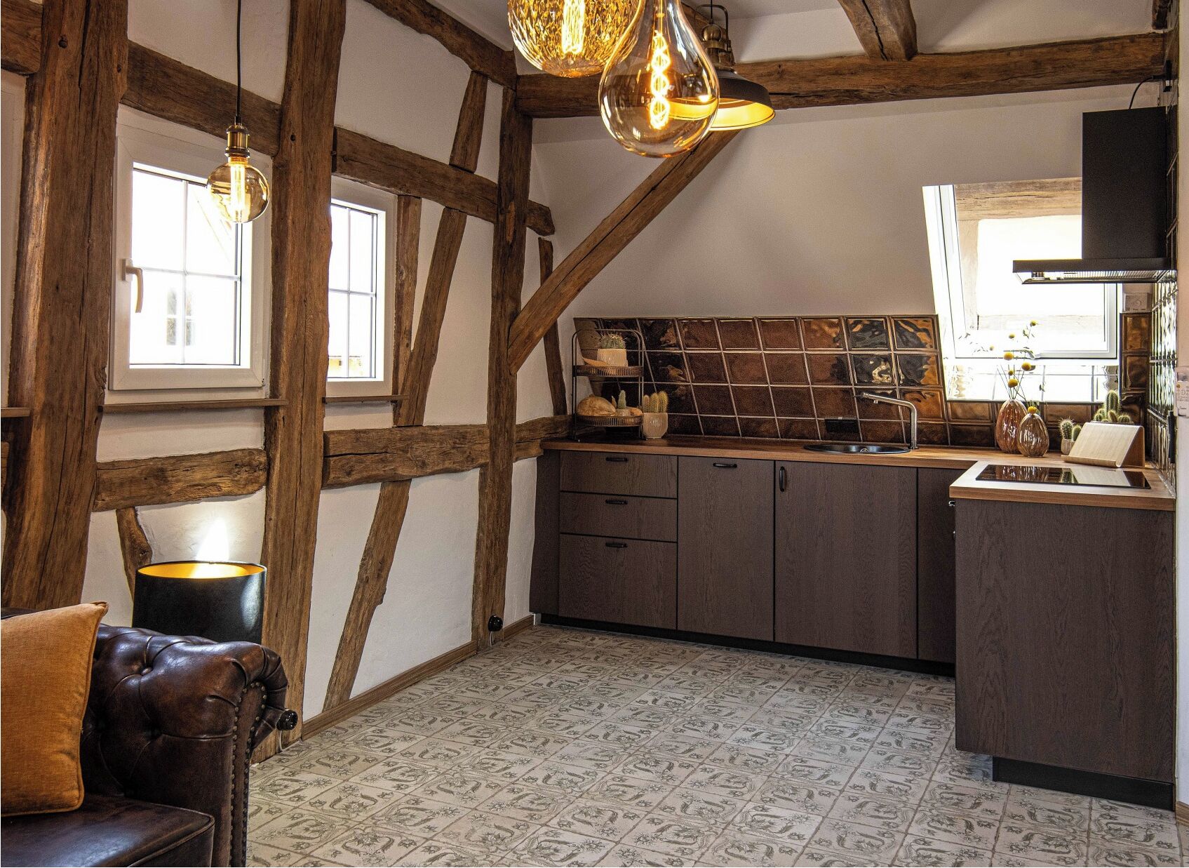 A rustic kitchen with exposed wooden beams, a tiled backsplash, and a modern countertop.