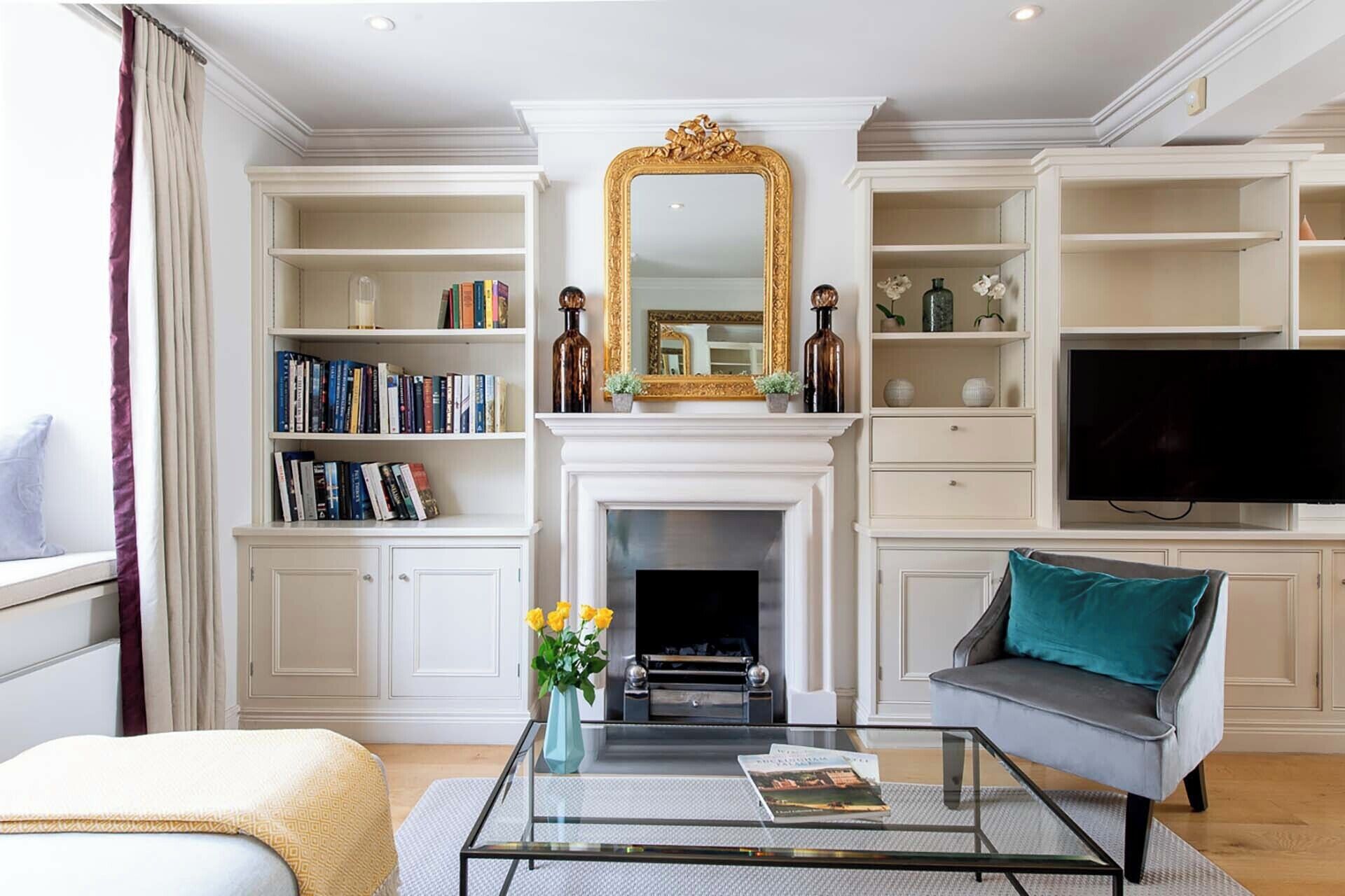 A living room with a fireplace, bookshelves, a television, and a sofa.