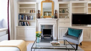 Una sala de estar con chimenea, estanterías, televisor y sofá.