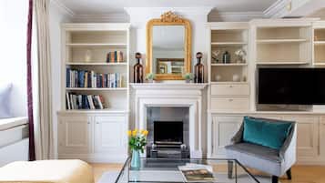 A living room with a fireplace, bookshelves, a television, and a sofa.