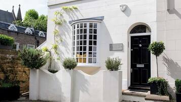 A white building with a black door, a window with a grid pattern, and a sign that reads "HOLLAND COTTAGE."