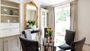 Una habitación con una mesa de comedor, dos sillas, un espejo y vistas al exterior.