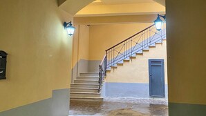 Una scala con ringhiera in legno e una porta blu sul fondo.