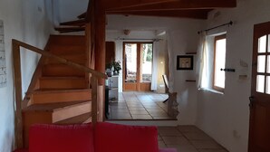 A wooden staircase leading to a room with a red couch, a tiled floor, and a wall-mounted bird illustration. - Character house Luberon, nature, swimming pool (Saint-Saturnin-lès-Apt)