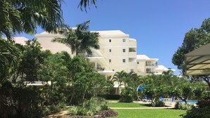 A hotel with multiple floors, surrounded by lush greenery and a swimming pool.