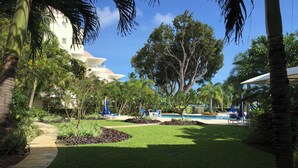 A pool area with lounge chairs and a pathway leading to a building.