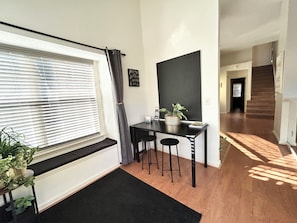 A room with a window, a table with a potted plant, and a staircase in the background.