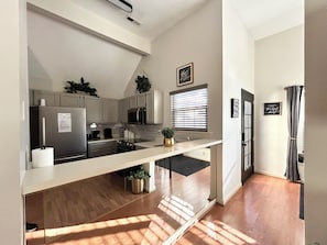 A modern kitchen with white cabinets, stainless steel appliances, and a wooden countertop.