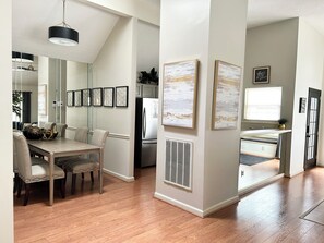 A modern kitchen with a dining area, wooden flooring, and a large window.