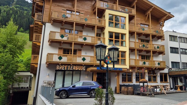 A multi-story wooden building with balconies and a sign reading "BREITERBUDE".