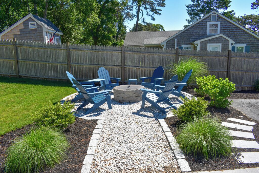A backyard with a fire pit, chairs, and a small shed.