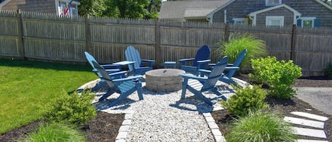 Un jardin avec un foyer, des chaises et un petit abri de jardin.