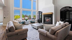A spacious living room with a fireplace, large windows, and a view of the outdoors.