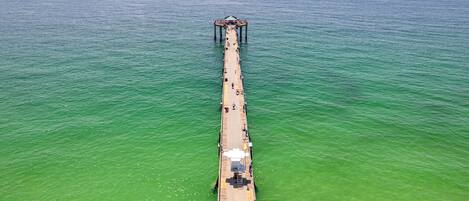 A pier extending into a greenish sea with a covered structure at the end.