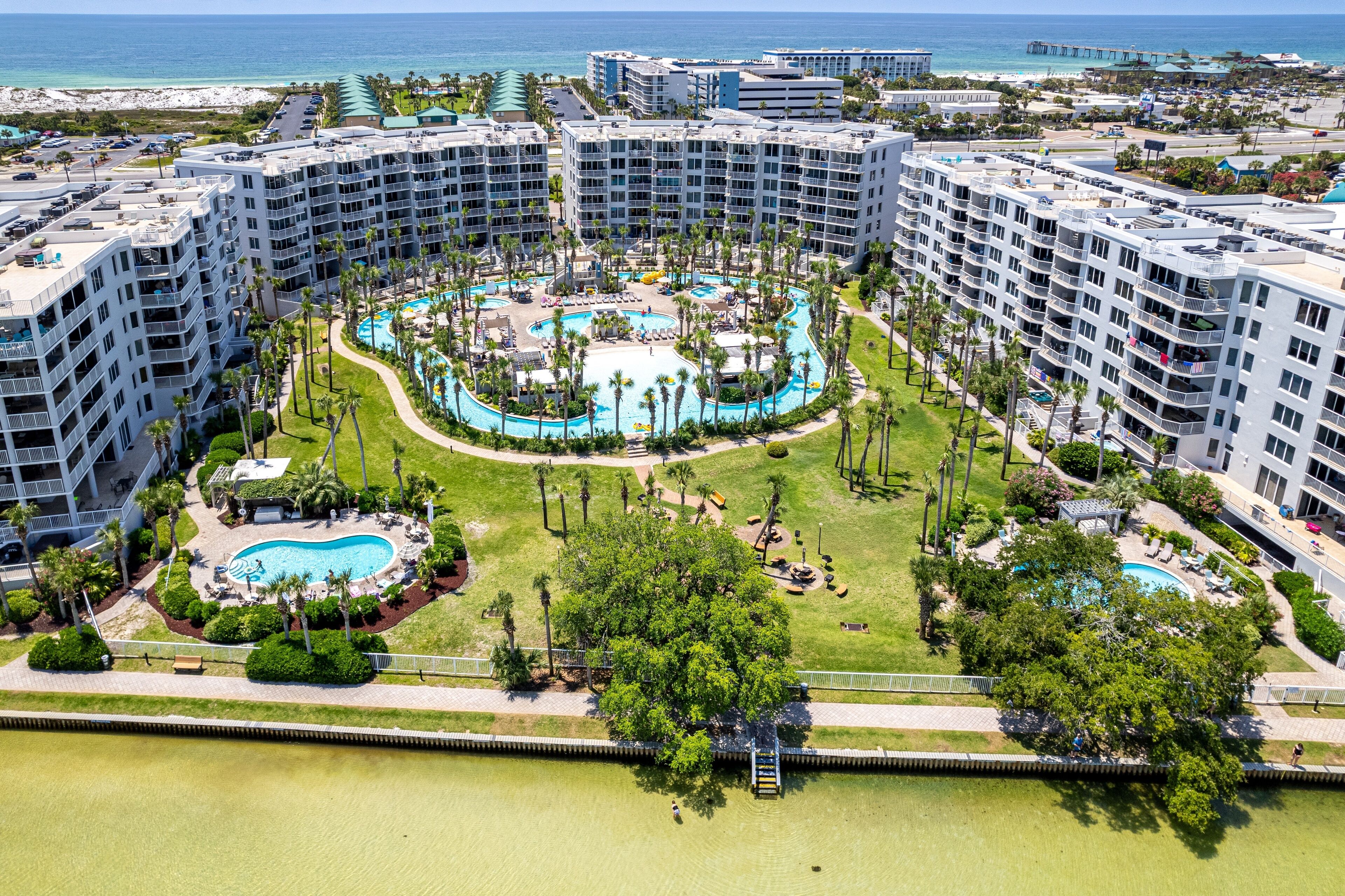 Un resort con varios edificios de gran altura, una piscina central y una zona de playa.