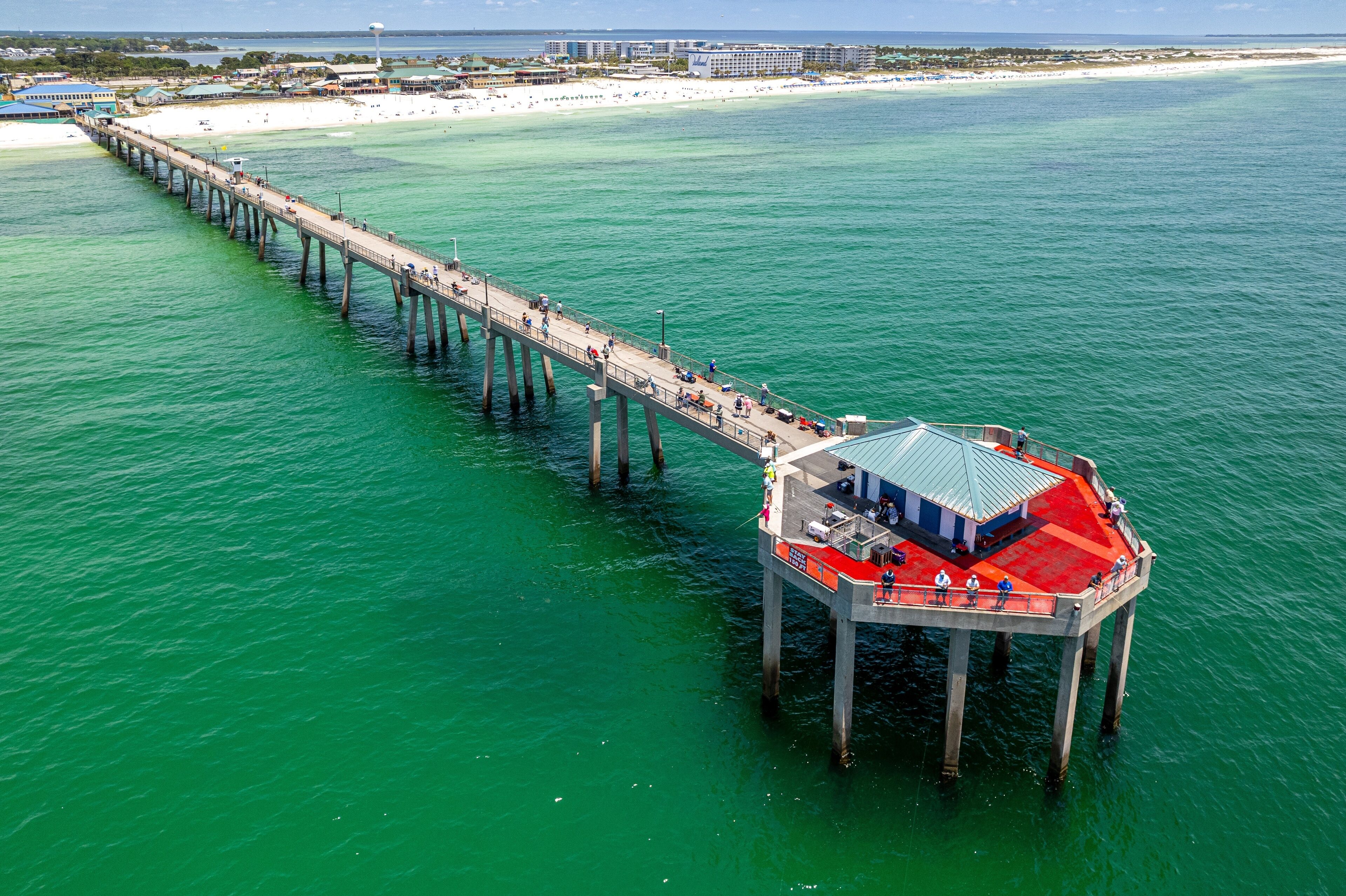 A pier extending into turquoise waters with a red-roofed structure at the end.