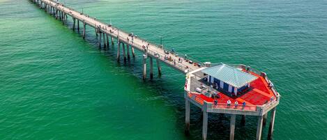 A pier extending into turquoise waters with a red-roofed structure at the end.