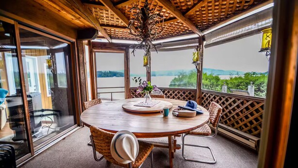 Una mesa de comedor de madera con sillas, una araña y vistas a un lago.