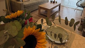 Un salon comprenant un canapé, une table basse et une table à manger, cette dernière étant mise avec de l’assiette et des couverts.