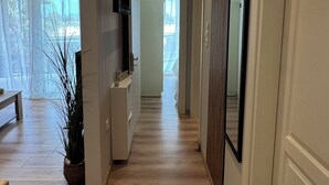 Un couloir doté d’un plancher en bois, d’un téléviseur à écran plat fixé au mur et d’une porte sur le côté droit.