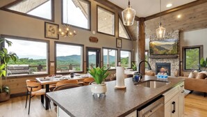 A spacious kitchen with a large island, a dining area with a view, and a fireplace.