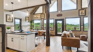 A spacious kitchen with a large island, dining area with a table and chairs, and a cozy seating area with a sofa and ottoman.